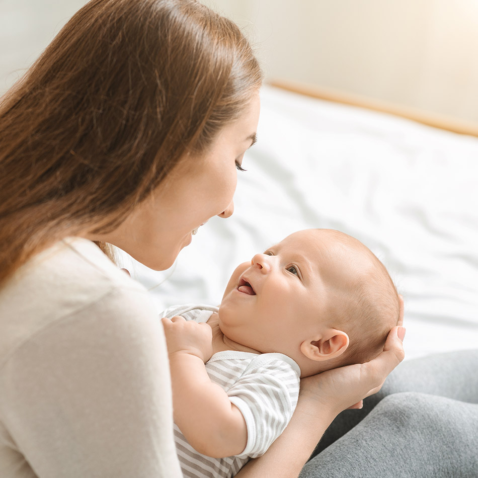 Cute newborn baby lying on mother's laps and looking at her with admire